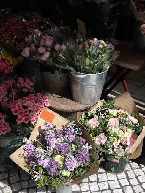 A collection of fresh flower bouquets displayed outdoors at a florist shop. The arrangements feature various floral varieties in soft pastel and vibrant shades, including pink roses, purple statice, a